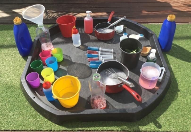 園庭のトレイに水と容器、道具だけを置いた遊びの環境